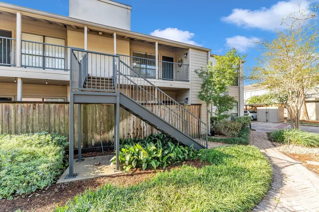 a view of a house with brick walls and flower plants in front of main door