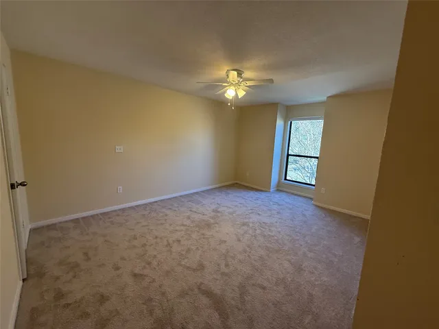 a view of an empty room with a chandelier fan