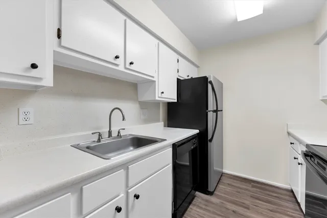 a kitchen with stainless steel appliances a sink a stove and a refrigerator with wooden floor