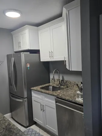 a kitchen with stainless steel appliances granite countertop a refrigerator a sink a stove and white cabinets