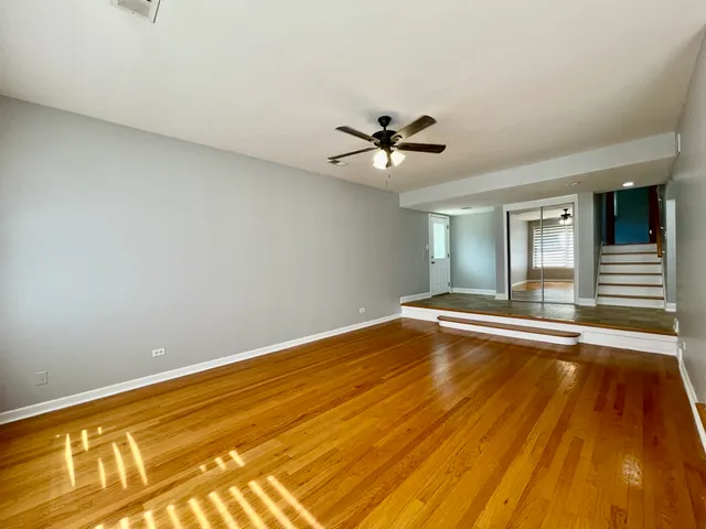 a view of a room with wooden floor and a ceiling fan
