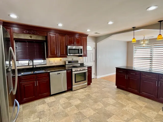 a large kitchen with stainless steel appliances granite countertop a stove a sink and a microwave