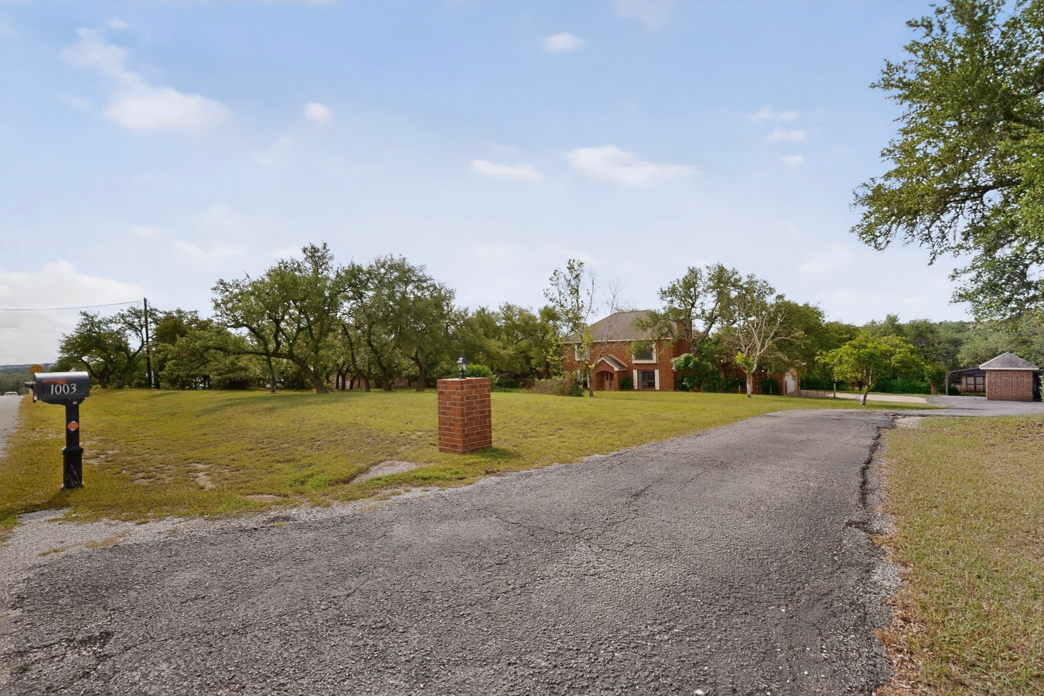 1003 Pier Branch Road Dripping Springs, TX 78620 - Photo 10 of 40 A long, private driveway leads to this charming brick residence nestled amidst a mature tree-filled property.