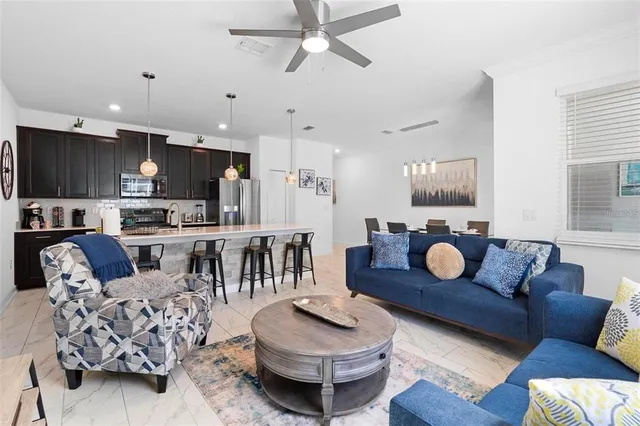 a living room with furniture kitchen view and a wooden floor