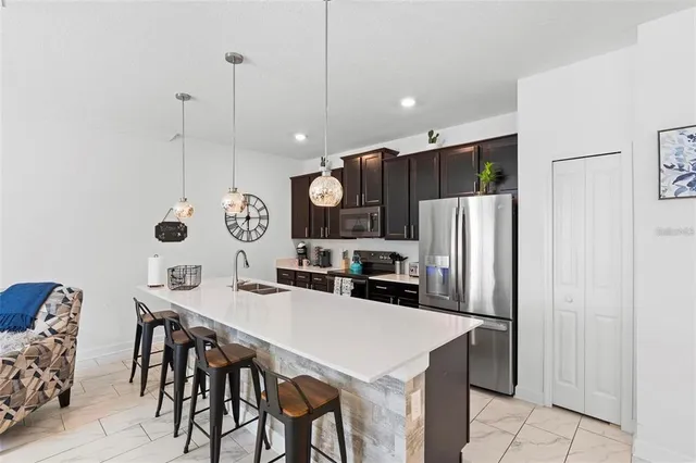 a kitchen with stainless steel appliances a table chairs and a refrigerator
