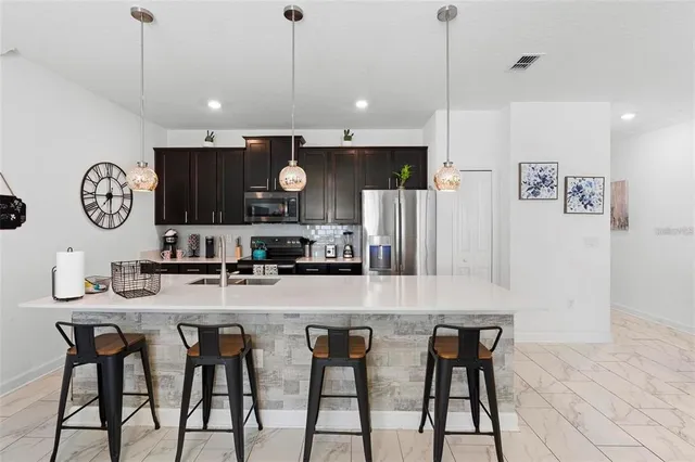 a kitchen with stainless steel appliances granite countertop a table chairs refrigerator and microwave