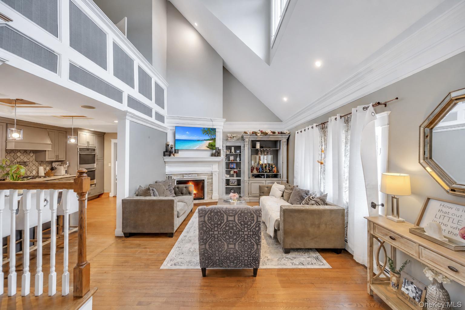 19 Joan Road Bay Shore, NY 11706 - Photo 6 of 50 Vaulted ceiling living area featuring a stone surround fireplace, hardwood flooring, recessed lighting, and a built-in display cabinet