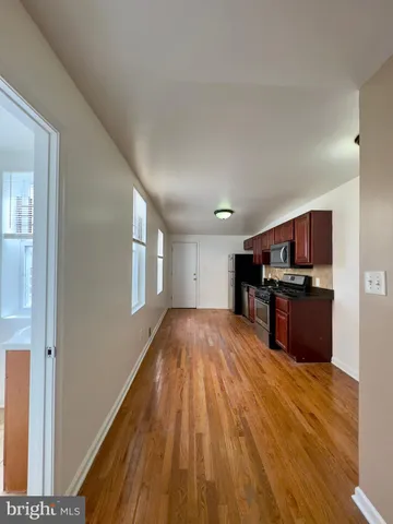 a view of kitchen with kitchen island wooden floor and stainless steel appliances