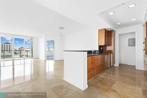 a view of a kitchen with kitchen island granite countertop wooden cabinets and a refrigerator