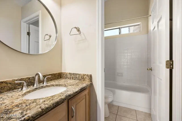 a bathroom with a granite countertop sink a toilet and a mirror