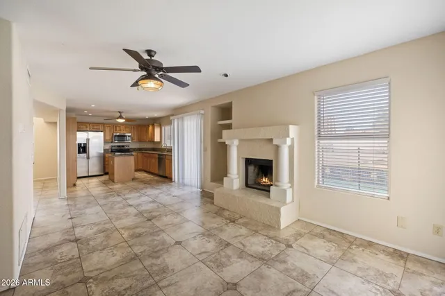 a view of a livingroom with a fireplace a ceiling fan and windows