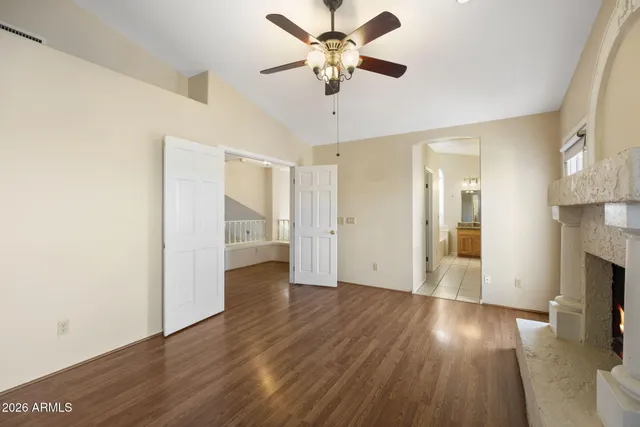 a view of an empty room with wooden floor and a ceiling fan