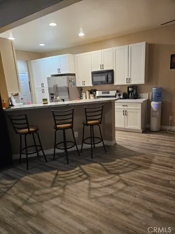 a kitchen with granite countertop a table chairs microwave and cabinets