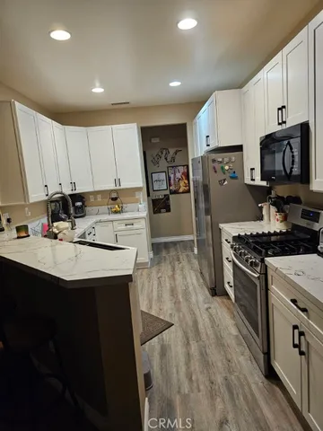 a kitchen with kitchen island white cabinets a sink a stove a refrigerator and a oven