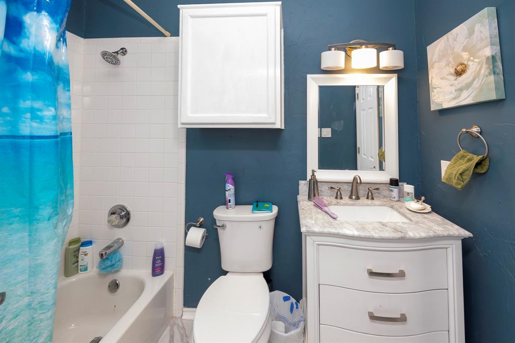1418 Signal Ridge Place Rockwall, TX 75032 - Photo 29 of 35 White subway tile shower surround with chrome fixtures, white built-in cabinetry, vanity with undermount sink and countertop, and a wall-mounted mirror with overhead lighting