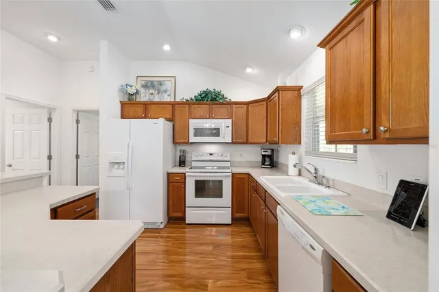 a kitchen with a refrigerator a stove top oven a sink and dishwasher with wooden floor