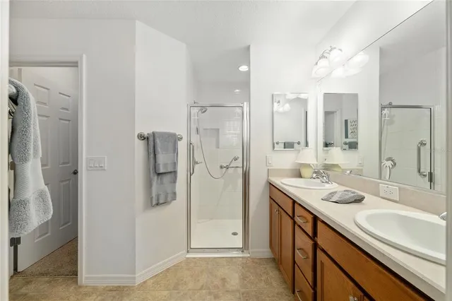 a bathroom with a double vanity sink a large mirror and shower