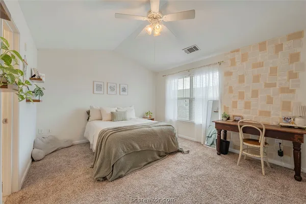 a spacious bedroom with a bed and ceiling fan