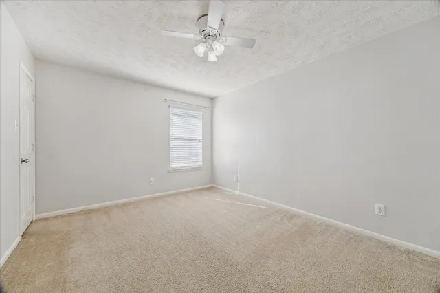 an empty room with windows and ceiling fan