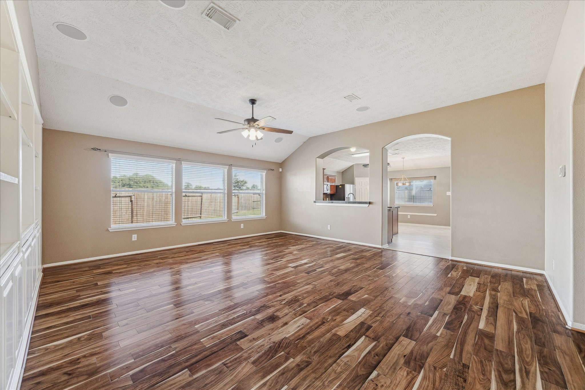 15203 Knotty Chestnut Street Cypress, TX 77429 - Photo 6 of 32 This view when entering the family room from the front entry, shows the laminate wood floor, high ceiling, triple windows overlooking the side yard and the entry to the kitchen & breakfast area.