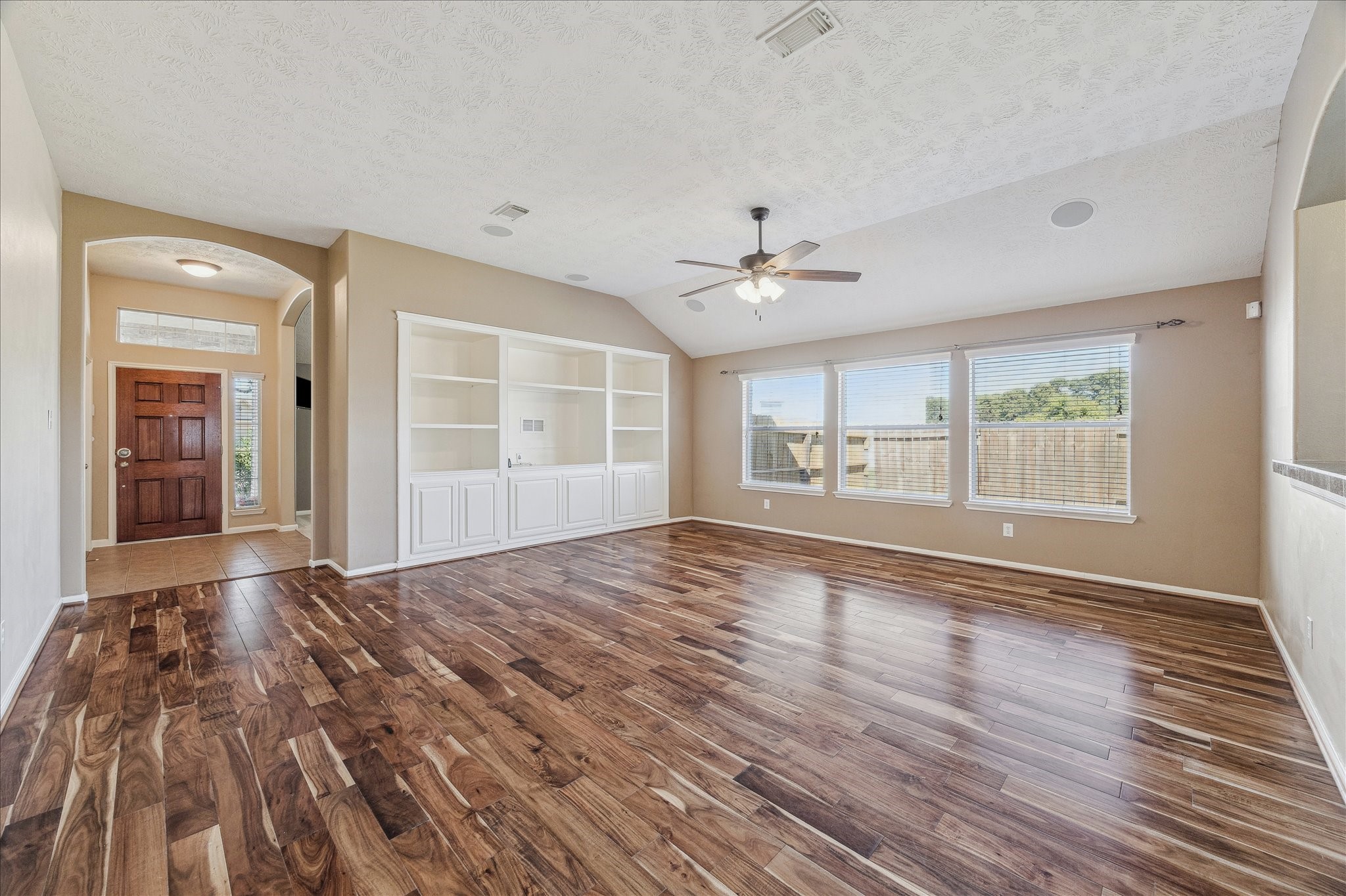 15203 Knotty Chestnut Street Cypress, TX 77429 - Photo 7 of 32 The family room features a large built-in entertainment center with upper level shelving and lower level cabinet storage. This view shows the arched doorway leading from the front entry foyer.