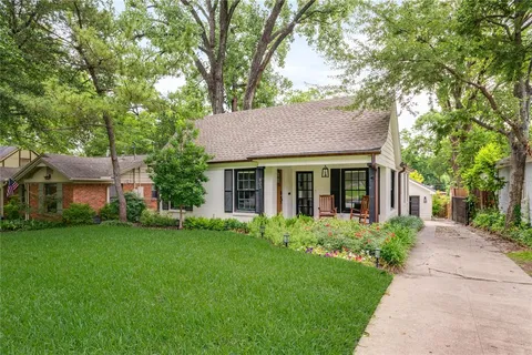 a front view of a house with a garden and trees