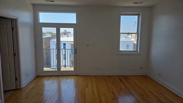a view of an empty room with closet and wooden floor