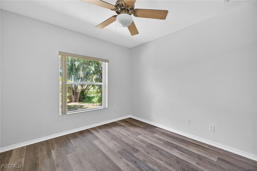 2007 Southwest 43rd Terrace Cape Coral, FL 33914 - Photo 18 of 22 an empty room with wooden floor chandelier fan and windows