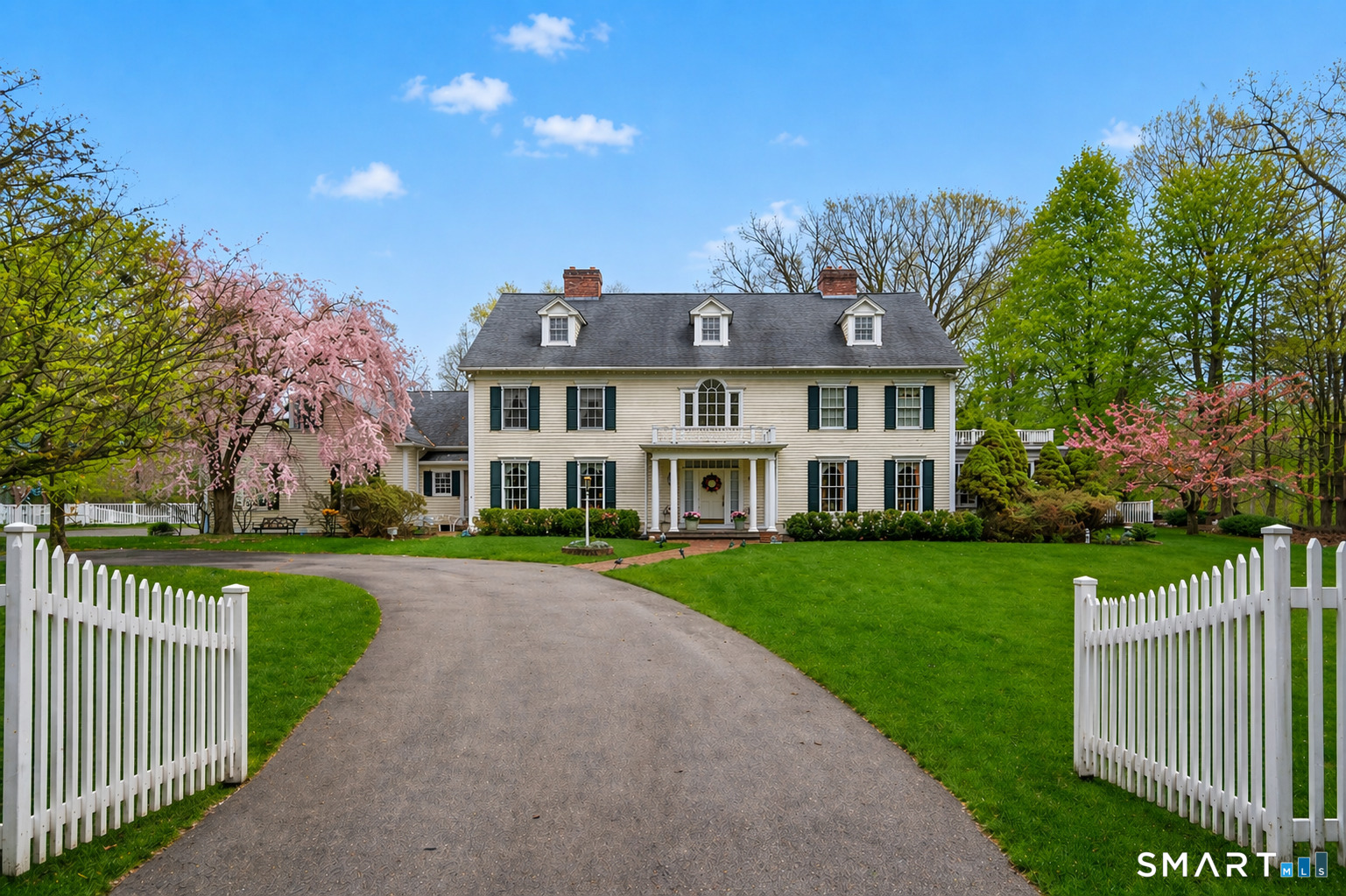 a view of a big house with a big yard and large trees