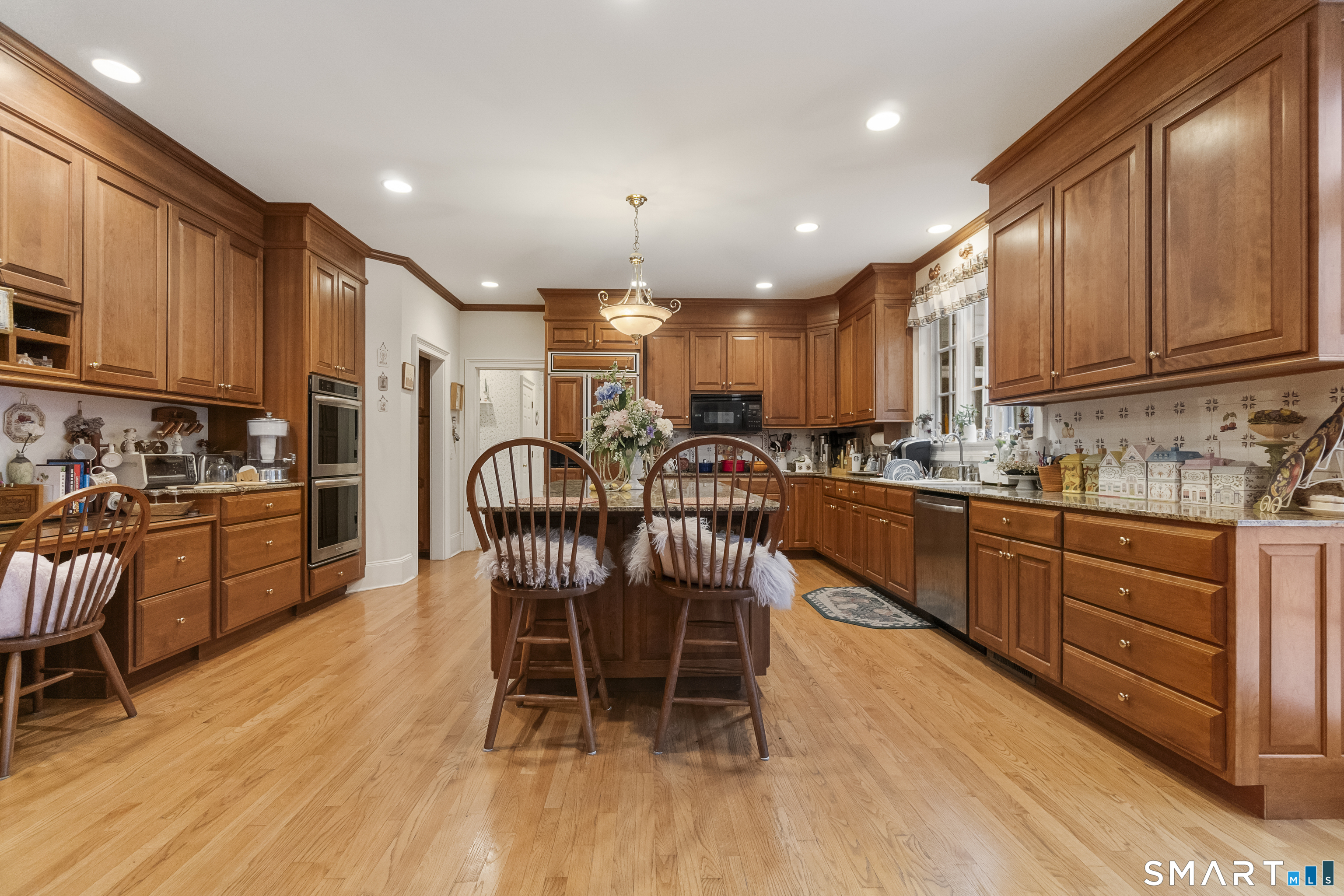 9 Perkins Road Woodbridge, CT 06525 - Photo 12 of 39 a kitchen with stainless steel appliances granite countertop a stove top oven a sink dishwasher a dining table and chairs with wooden floor