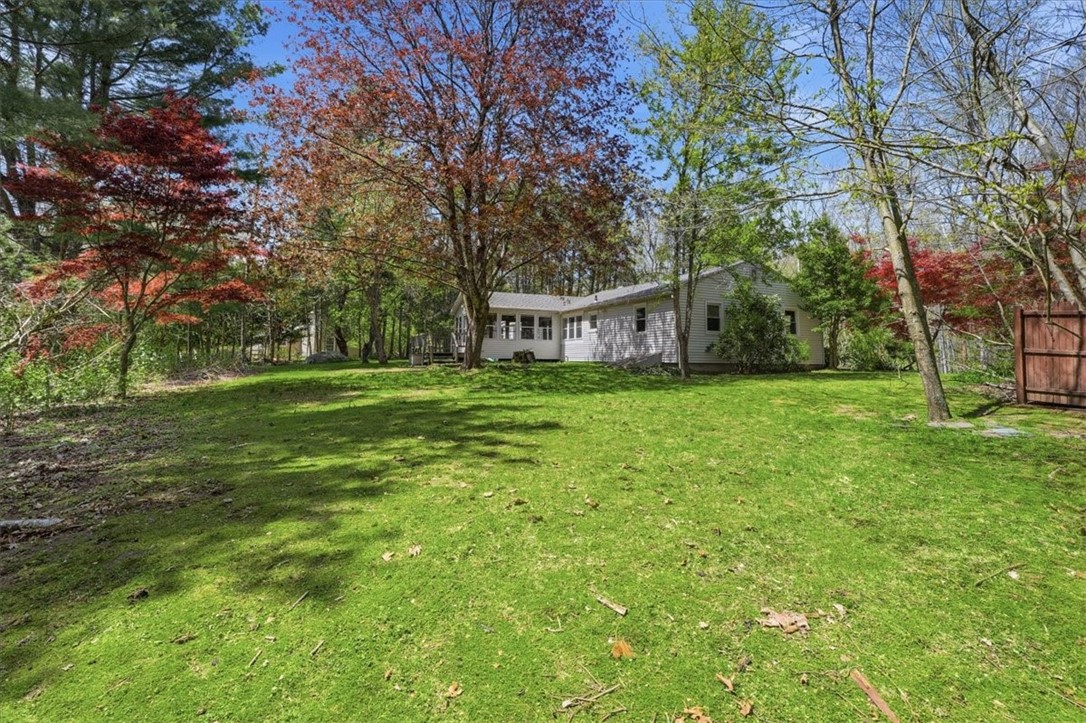 322 Rocky Hill Road Scituate, RI 02857 - Photo 45 of 50 Nestled among mature trees, this backyard offers a tranquil, wooded setting filled with natural beauty. Flowering shrubs and established plantings create seasonal color and charm, while the open lawn provides space to enjoy the outdoors.