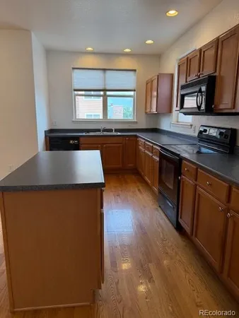 a large kitchen with stainless steel appliances a large counter top a stove a microwave a sink and a refrigerator