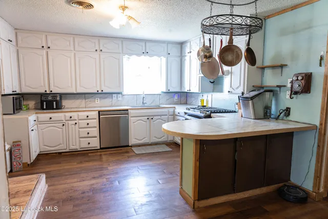 a kitchen with a sink dishwasher a stove a microwave oven with a dining table and chairs