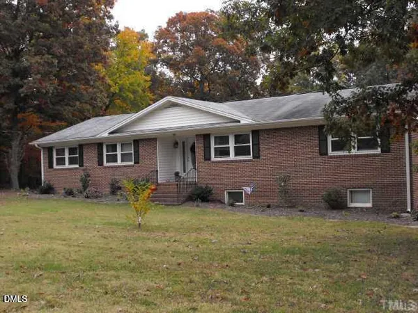a front view of a house with yard and trees