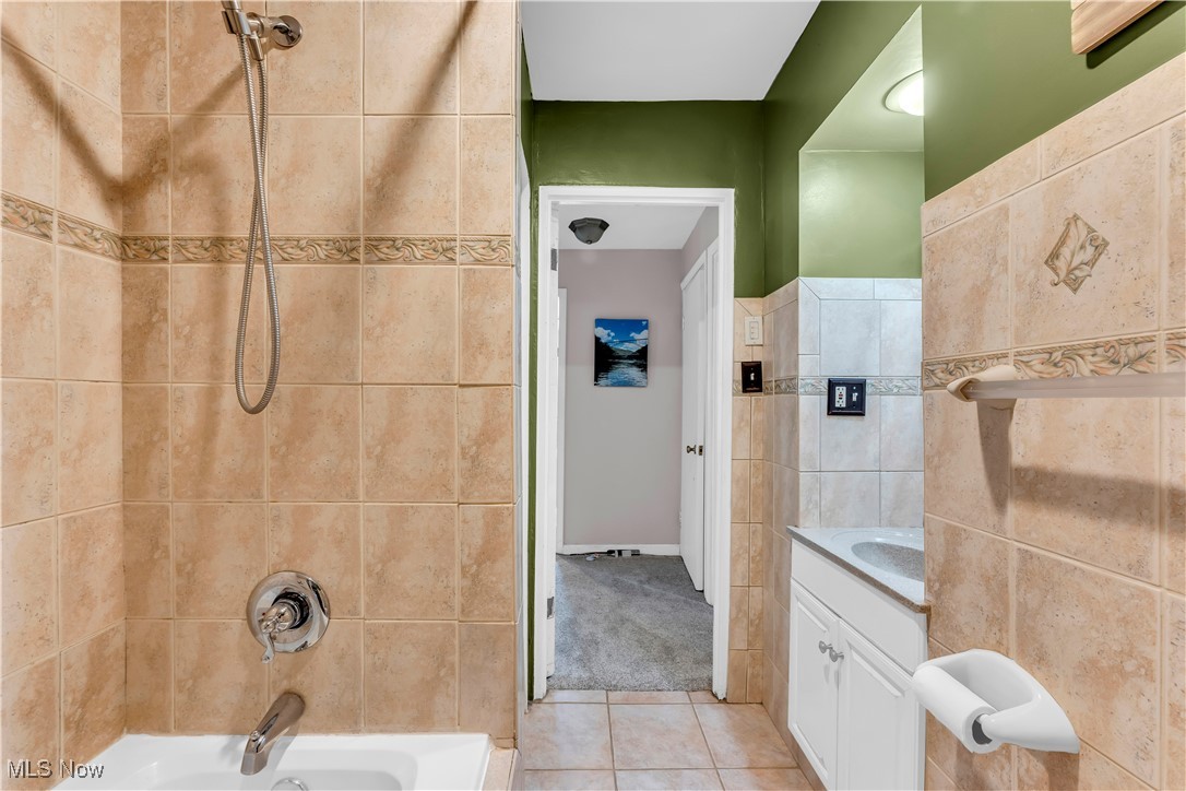 7479 Macedonia Road Bedford, OH 44146 - Photo 30 of 42 Bathroom with tile walls, tiled shower / bath combo, vanity, and tile patterned floors