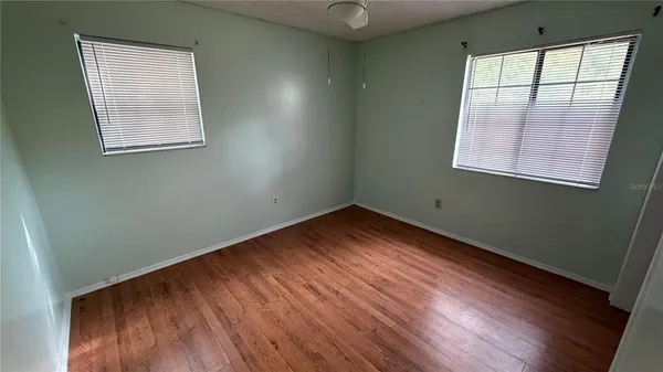 en empty room with wooden floor and windows