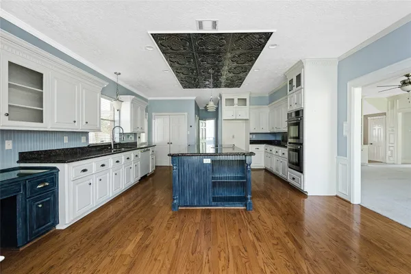 a kitchen with stainless steel appliances granite countertop a stove a sink dishwasher and a oven with white cabinets
