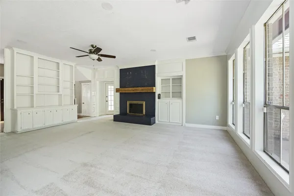 an empty room with windows and fireplace