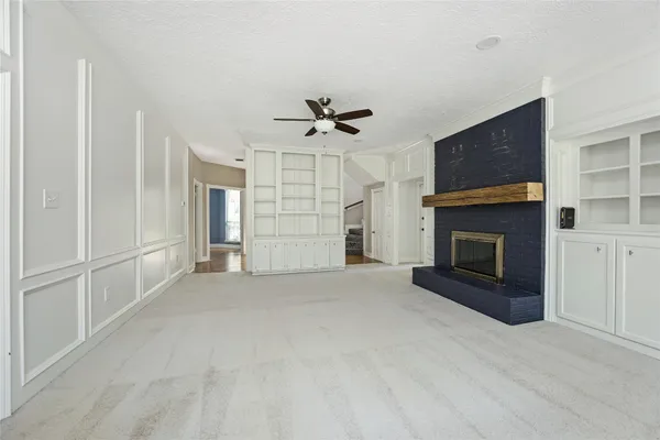 an empty room with fireplace cabinet and windows