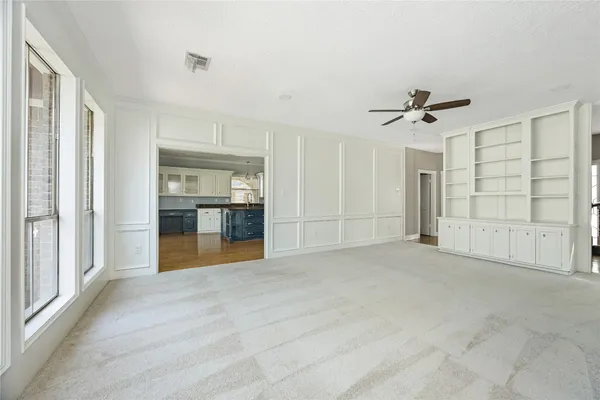 a view of empty room with wooden cabinet and windows