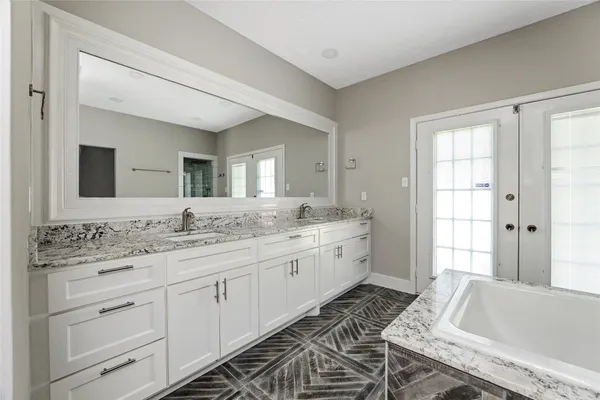 a spacious bathroom with a granite countertop sink a mirror and a bathtub