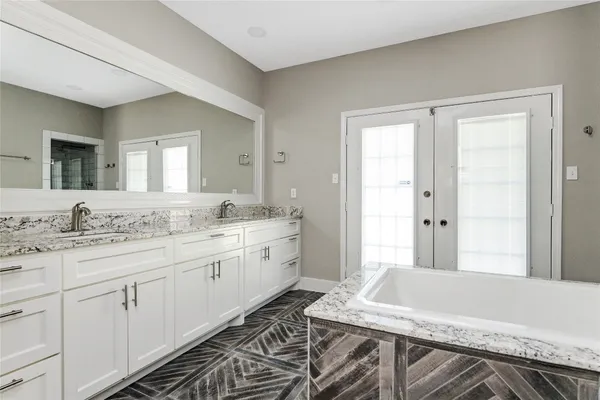 a bathroom with a granite countertop sink a large mirror and a bathtub