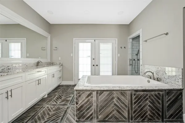 a bathroom with a granite countertop sink a large mirror and a bathtub