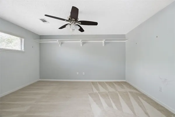 a spacious bedroom with a large bed and a chandelier fan