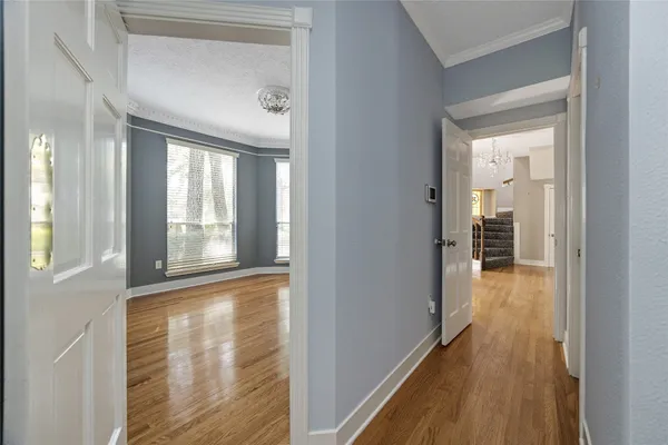 a view of a hallway with wooden floor and a bathroom