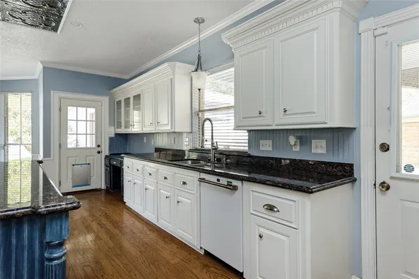 a kitchen with granite countertop a sink a stove and cabinets