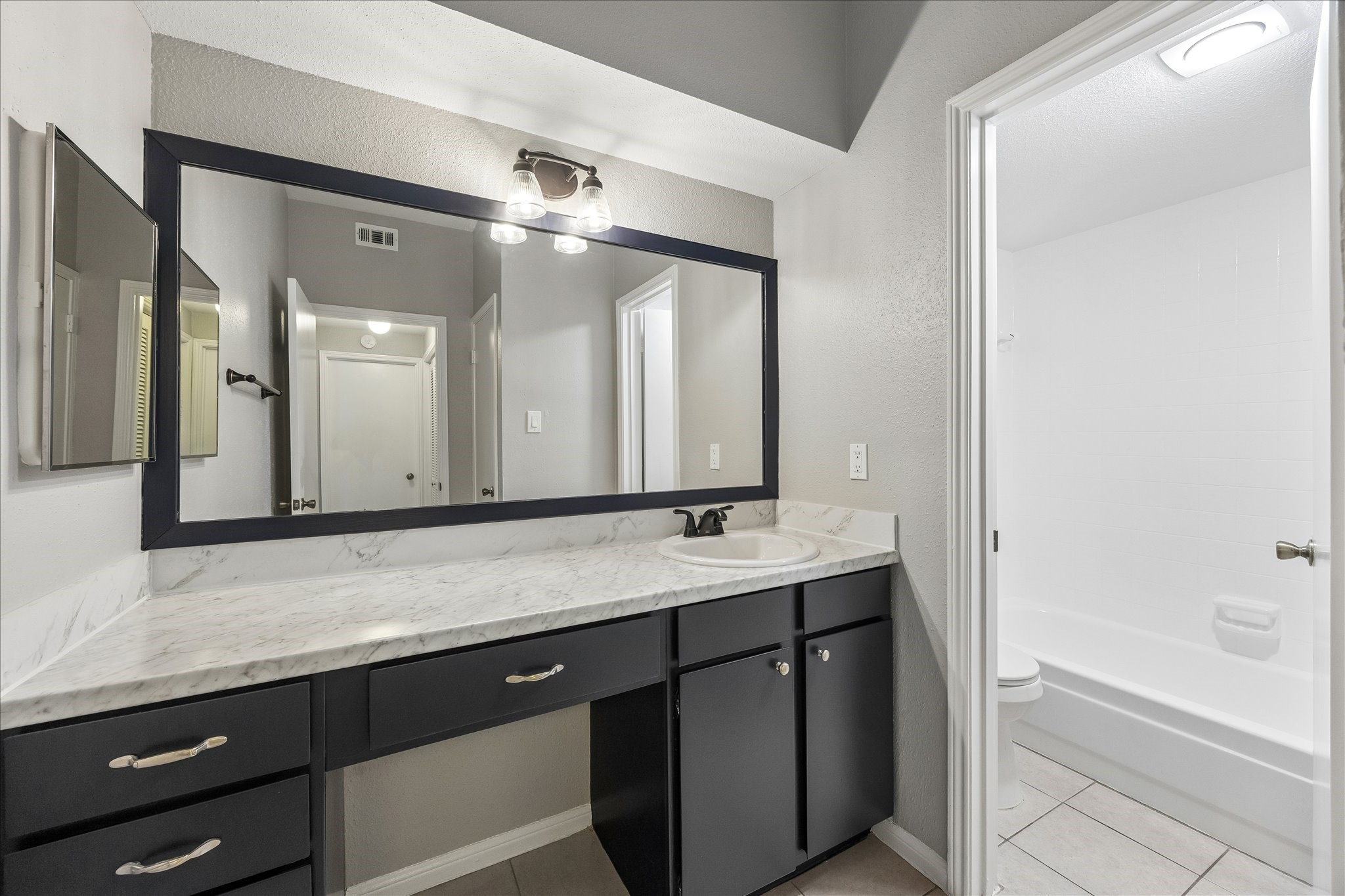 2100 Tanglewilde Street, Unit 124 Houston, TX 77063 - Photo 10 of 20 a bathroom with a granite countertop sink mirror and a bathtub