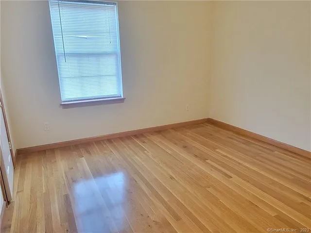 an empty room with wooden floor closet and windows