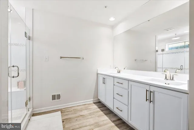 a spacious bathroom with a double vanity sink a mirror and a shower