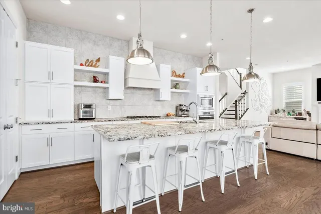 a kitchen with stainless steel appliances granite countertop a sink a stove a refrigerator and island with wooden floor